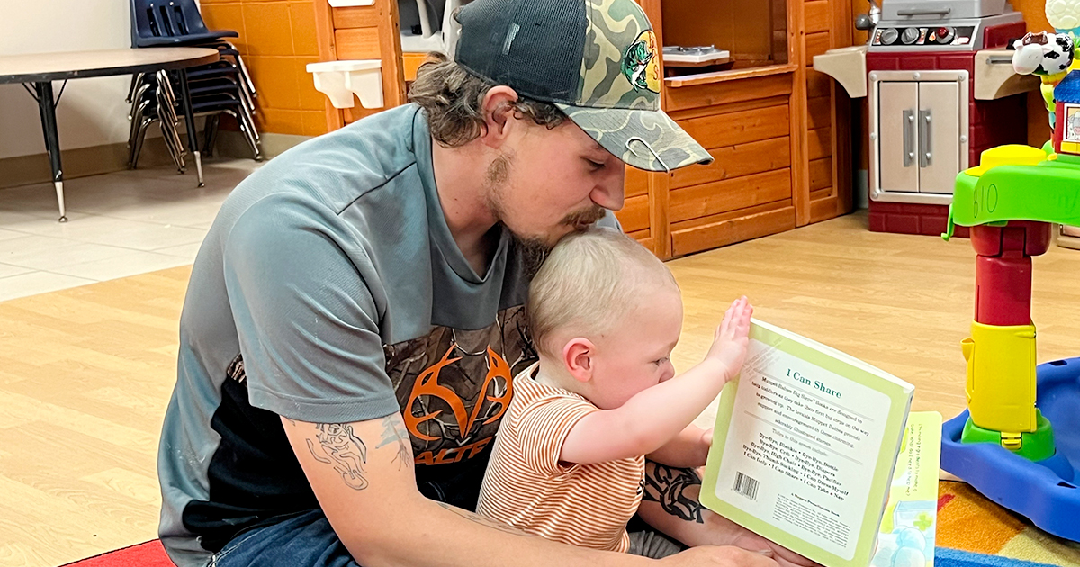 A father and baby play together with a book
